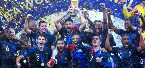 French national football team celebrating their 2018 FIFA World Cup victory, lifting the trophy amidst confetti and excitement.