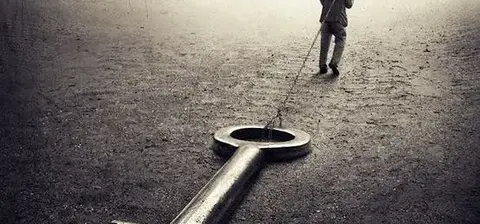 A lone figure walks away while dragging a large, oversized key across a barren landscape, symbolizing themes of struggle or searching for meaning.