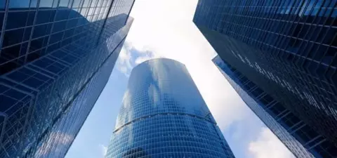 Skyscrapers with glass facades towering against a blue sky, creating a dramatic perspective from ground level.