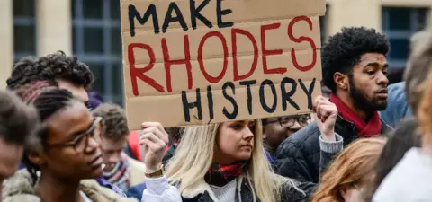 A protest scene with a diverse crowd holding a sign that reads 
