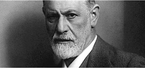 A close-up portrait of Sigmund Freud, featuring his intense gaze and distinguished beard, set against a softly blurred background.
