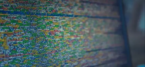 A close-up of a laptop screen displaying colorful lines of coded text, showcasing programming code or data.