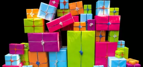 A colorful pile of wrapped presents in various sizes and vibrant colors, including pink, green, blue, and orange, arranged in a visually appealing display.