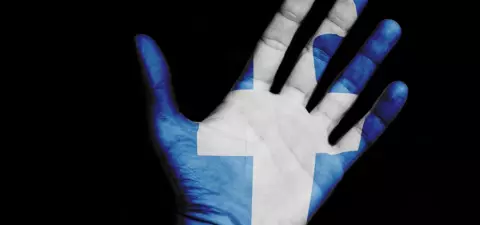 A hand painted with the blue and white colors of the Finnish flag, displaying a prominent cross symbol, set against a black background.