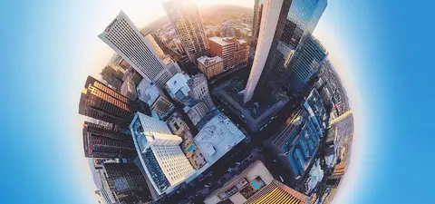 A panoramic view of a city skyline captured from above, showcasing modern skyscrapers and urban architecture under a bright sky.