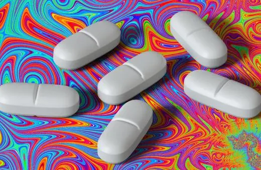 Six white pills arranged against a vibrant, psychedelic swirl background of various colors.