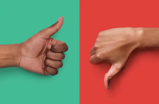 A close-up of two hands: one giving a thumbs up on a green background and the other giving a thumbs down on a red background.