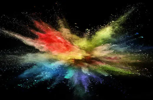 A vibrant explosion of colorful powders creating a dynamic burst effect against a black background.