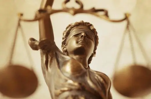A close-up of a bronze statue of Lady Justice, holding a scale and wearing a blindfold, symbolizing fairness and impartiality in law.