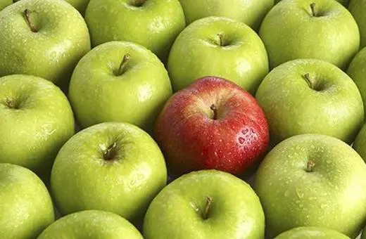 A cluster of green apples with one prominent red apple in the center, showcasing a vibrant contrast in color and texture.
