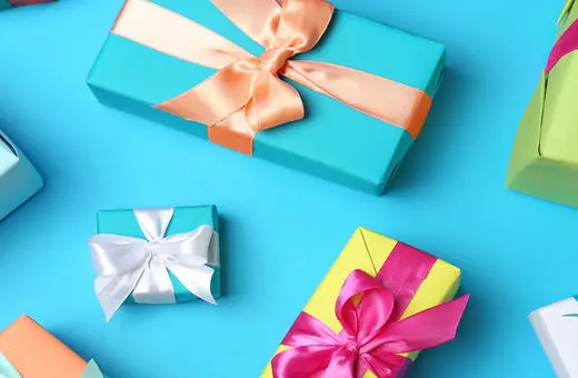 A variety of colorful wrapped gift boxes with ribbons on a bright blue background, creating a festive atmosphere.