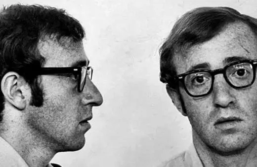 Black and white mugshot of a man with glasses, showing both profile and frontal views, resembling a 1970s style portrait.