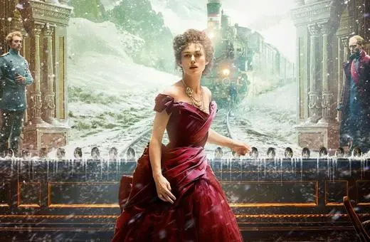 A woman in a red gown stands on a snowy train platform, with a vintage train in the background and two men observing her.