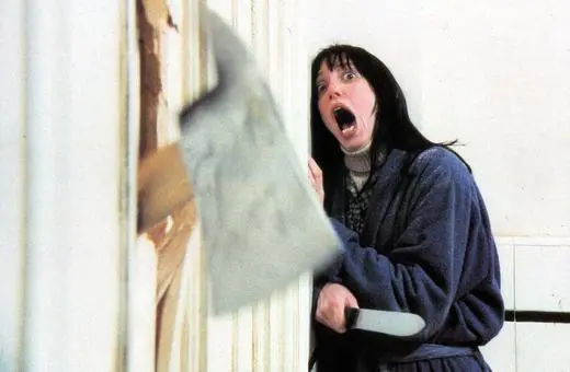 A woman in panic, wielding a large knife, appears to be breaking through a door, evoking a sense of horror and tension.